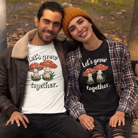 "Let's Grow Together" Tee by Trippy Outfitters. This heartwarming design features two mushrooms growing side by side, symbolizing growth, connection, and togetherness. Perfect for friends, couples, or anyone who values shared growth.